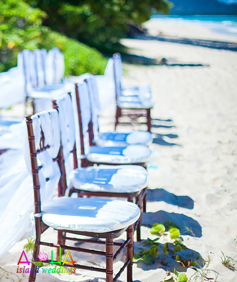 dark wood chairs on the beach with white material